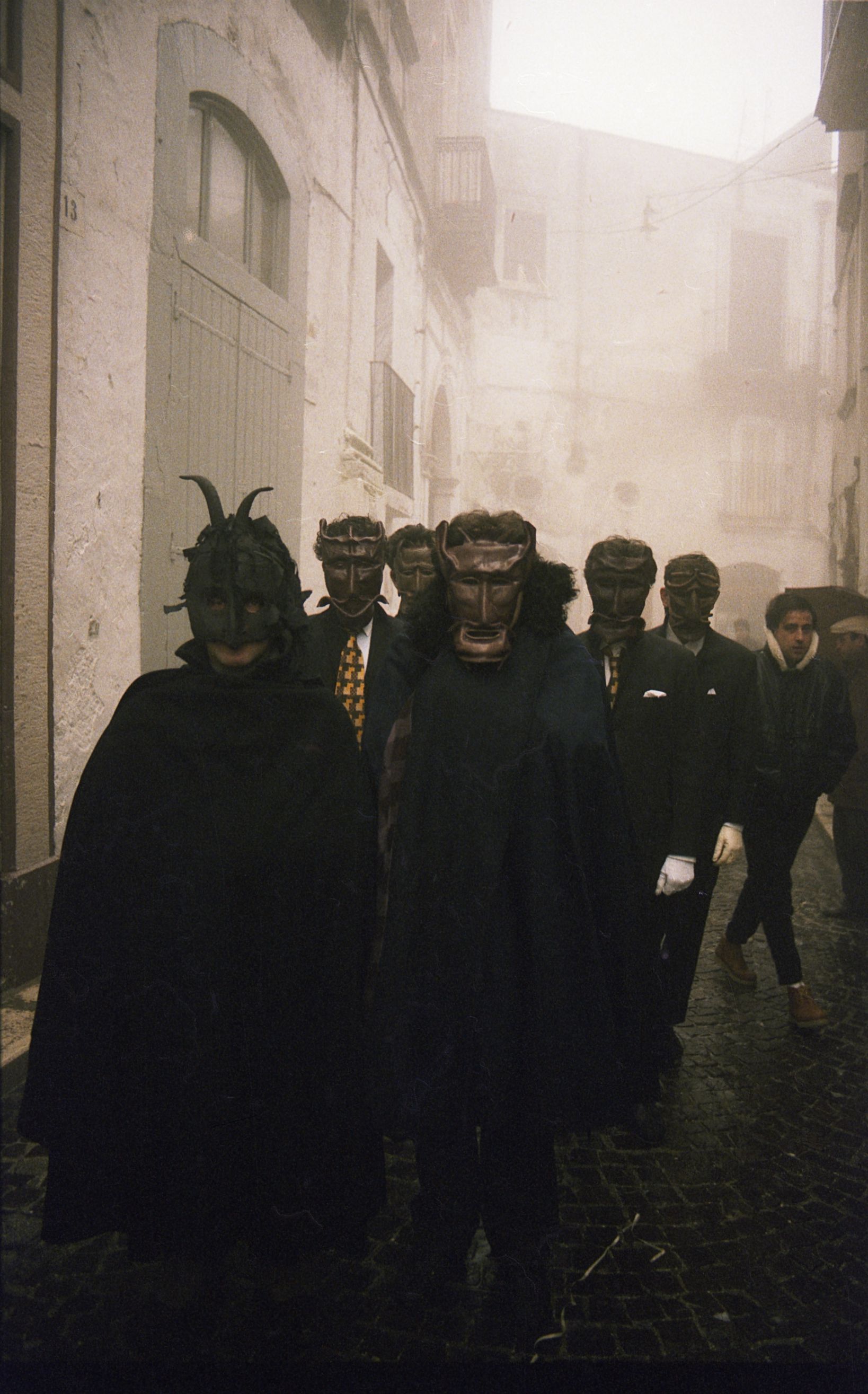 Procession in 1983 of people wearing masks created by Mimmo Palena