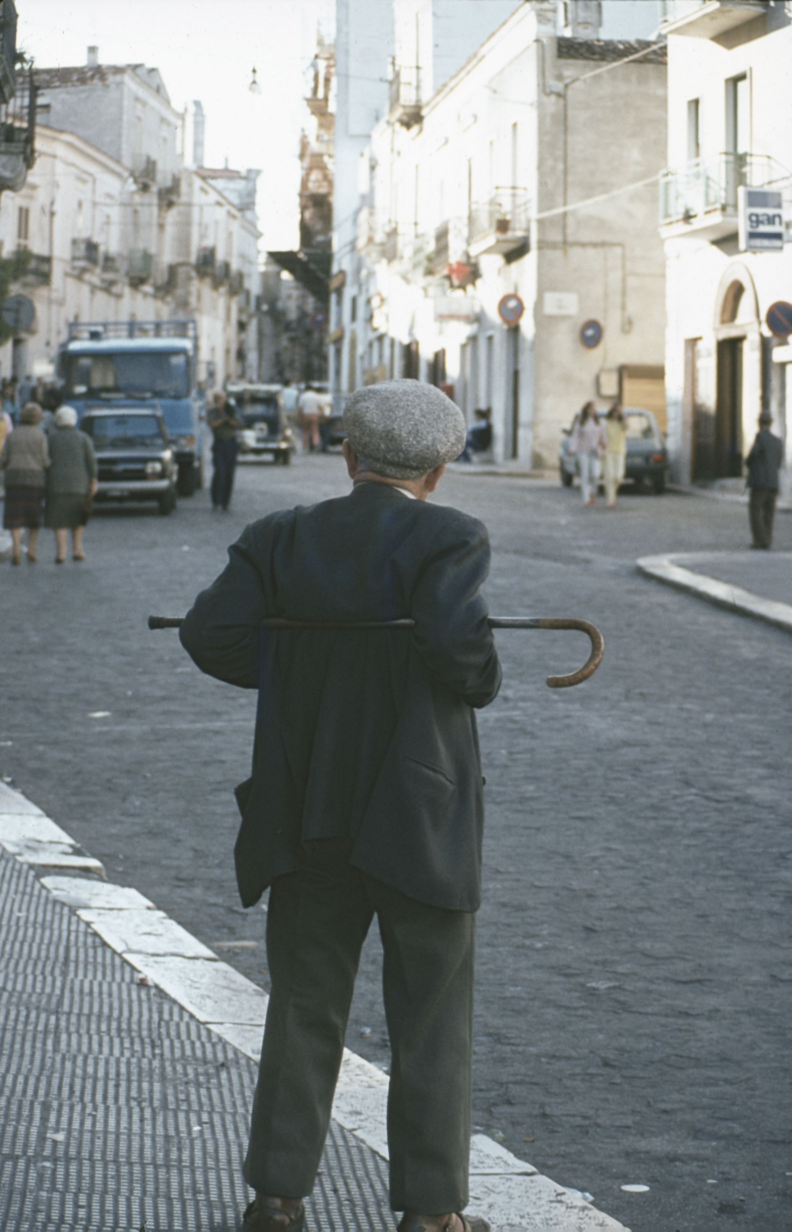 An old man with his cane behind his back looking up the Corso in Monte Sant'Angelo
